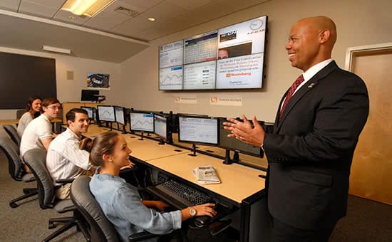 A professor teaching students in front of computer screens