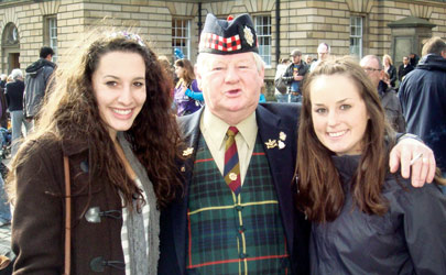 Students posing with a man dressed in traditional Scottish attire