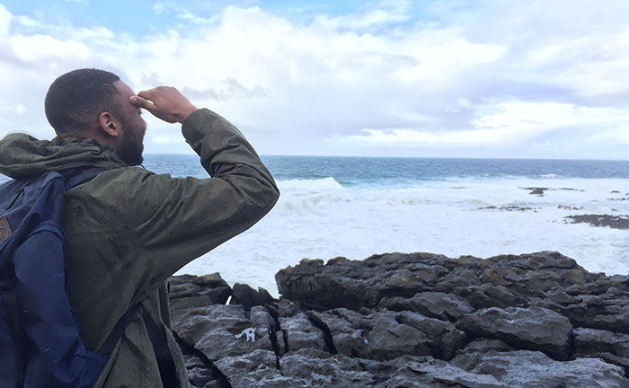 Student shading his eyes as he looks out across a rocky shore on the Irish countryside