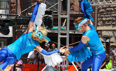 Dancers dressed in bright blue costumes with bird masks performing outdoors