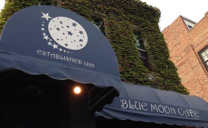 A deep blue storefront awning with branding for the Blue Moon Cafe in Fells Point, Baltimore